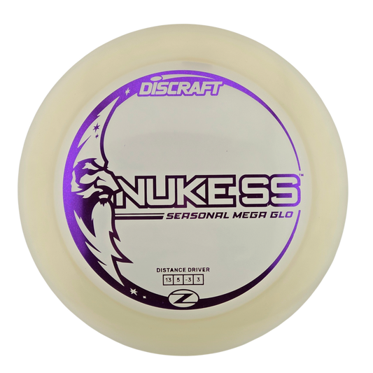 A Discraft Nukess Seasonal Mega Glo distance driver disc golf disc, featuring a translucent off-white plastic body with a purple and black printed graphic on a white background.